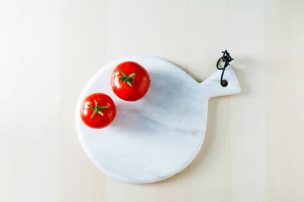 Δύο κόκκινες ώριμες ντομάτες σε ένα μαρμάρινο σκάφους σε ένα τραπέζι κουζίνας της Λι — Φωτογραφία Αρχείου