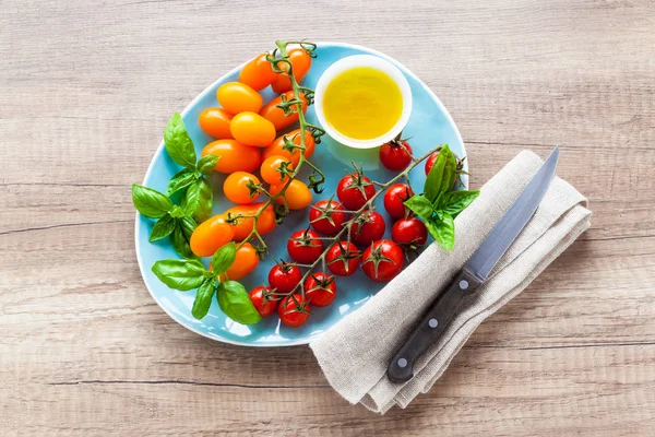 Kirschtomaten und Basilikumblätter auf einem blauen Teller auf einem — Stockfoto