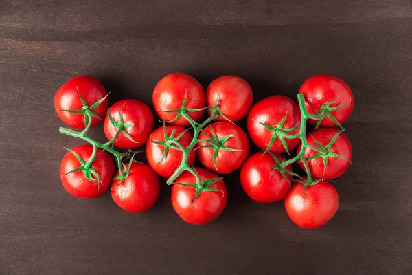 Uma pilha de tomates vermelhos frescos, maduros e deliciosos Numa madeira castanha . — Fotografia de Stock
