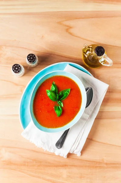 Ahşap zemin üzerinde mavi bir kapta domates çorbası. Üstten Görünüm. Kopya 