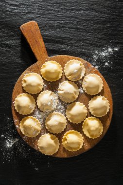 siyah taş zemin ahşap bir gemide pişmemiş mantı.