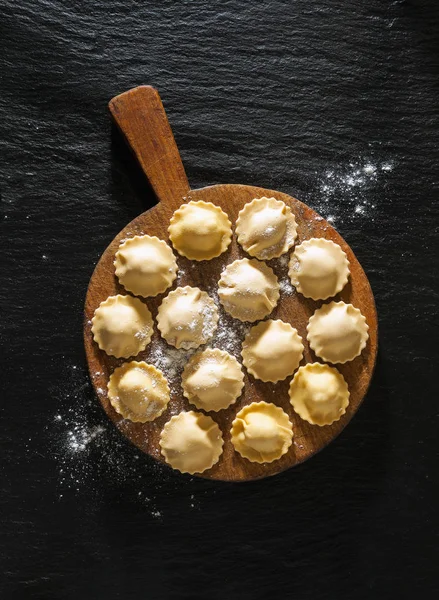 siyah taş zemin ahşap bir gemide pişmemiş mantı.