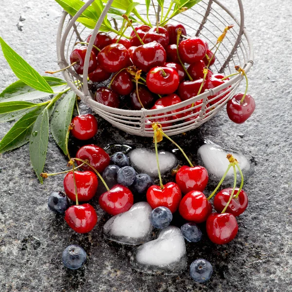 basket with fresh juicy Berries and ice cubes in the shape of he