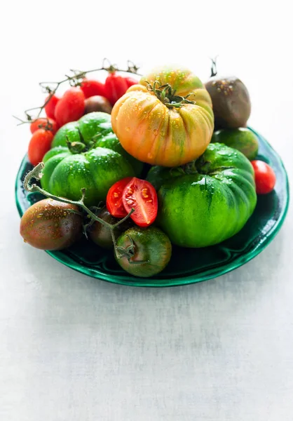 Olika sorters tomater på en platta på en vit sten tabell. f — Stockfoto