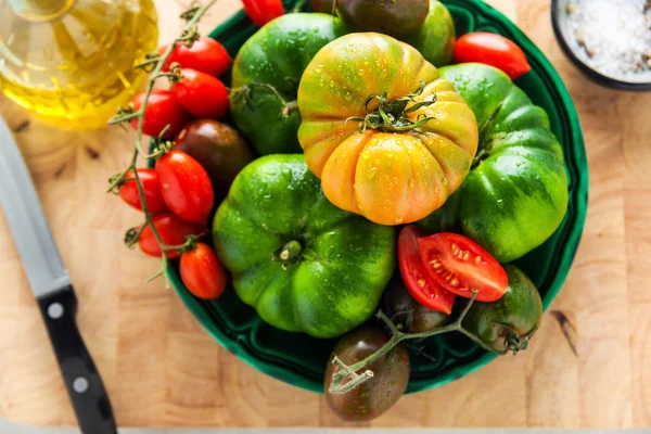 Different kinds of tomatoes on a plate on a white stone table. f — Stock Photo, Image