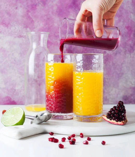 Despejando suco de romã em dois copos com p recentemente espremido — Fotografia de Stock