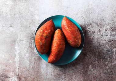 üç tatlı tüm çiğ turuncu patates mavi tabakta. hasat o