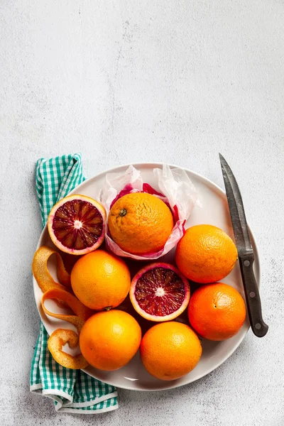 Группа апельсинов на тарелке. Некоторые из них обрезаны. нож и полотенце — стоковое фото