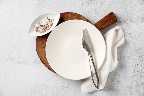 Placa vacía y cubiertos en una tabla de cortar de madera. un tenedor, un kni — Foto de Stock