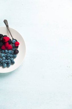 Beyaz tabak içinde çeşitli taze yaz meyveleri ile meyve salatası. T