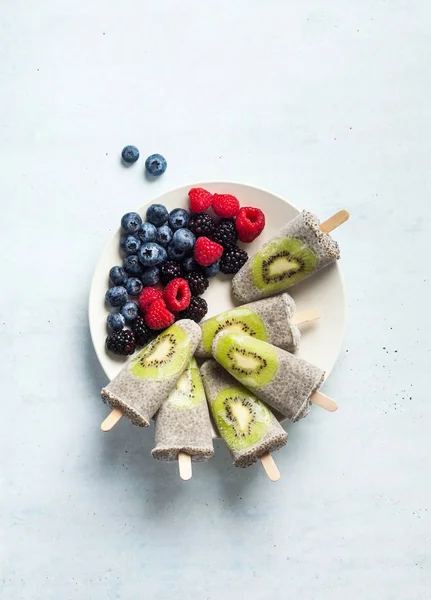 Kiwi Coconut Chia Popsicles and fresh ripe forest berries on the — Stock Photo, Image