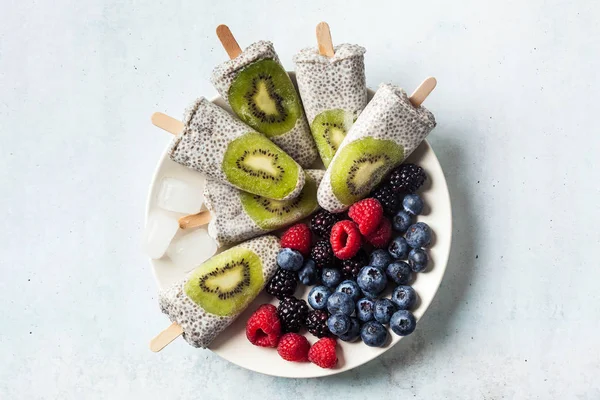Kiwi Coconut Chia Popsicles and fresh ripe forest berries on the — Stock Photo, Image