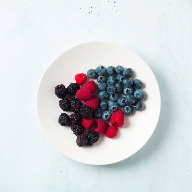 Beyaz tabak içinde çeşitli taze yaz meyveleri ile meyve salatası. T