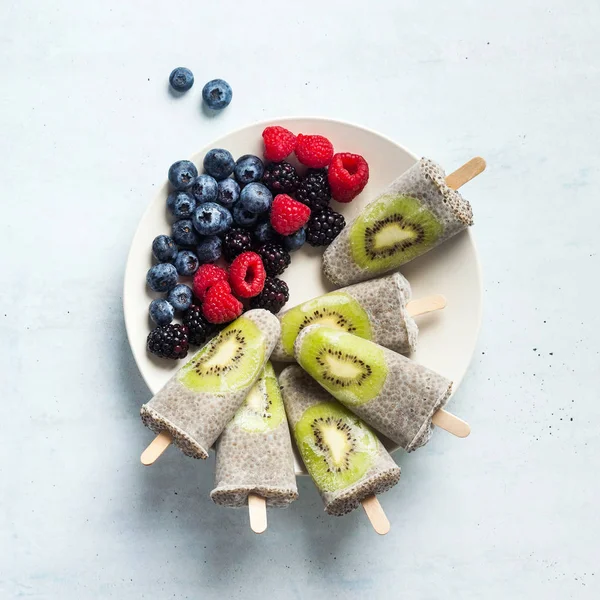 Kiwi Coconut Chia Popsicles and fresh ripe forest berries on the — Stock Photo, Image