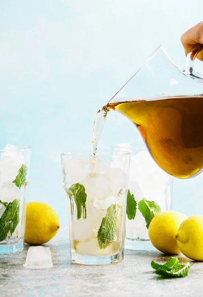 Tuangkan dari pitcher es teh tradisional dengan lemon dan es dalam tal — Stok Foto