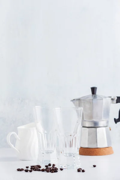 Vasos vacíos y una jarra de leche con granos de café y cafetera — Foto de Stock