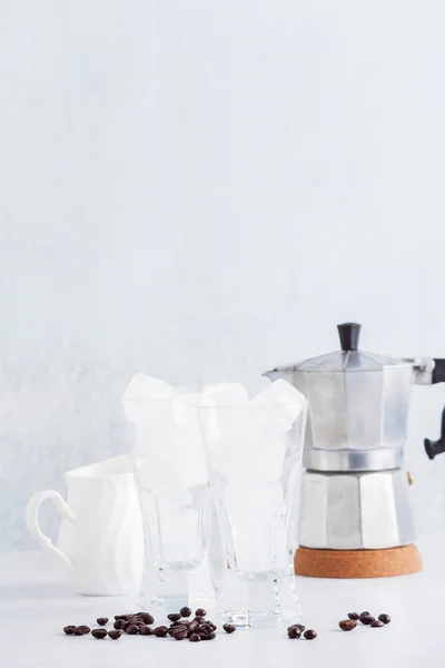 Dos vasos vacíos de hielo sobre la mesa. y una cafetera en el — Foto de Stock