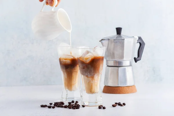 Pour milk in cold brew coffee on the table. coffee pot in the ba