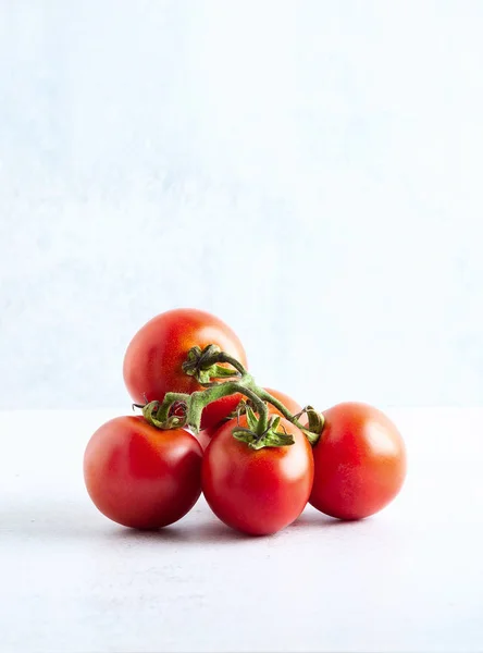 Um ramo de tomates frescos maduros em uma mesa feita de pedra . — Fotografia de Stock