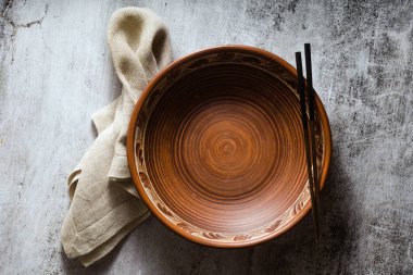 Karanlık bir arka planda boş kil tabağı ve yemek çubukları. satır