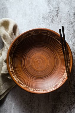 Karanlık bir arka planda boş kil tabağı ve yemek çubukları. satır