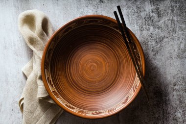Karanlık bir arka planda boş kil tabağı ve yemek çubukları. satır