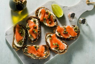 Çavdar ekmekli sandviç, füme somon ve mermer üzerinde kapari.