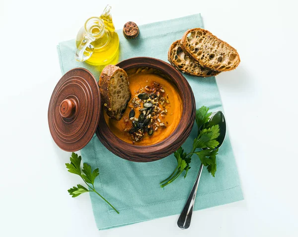 Pumpkin soup with seeds and fresh rye bread in a clay bowl on a — 스톡 사진