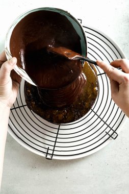 Pastanın üzerine çikolata ganache dökmek. kadın elleri