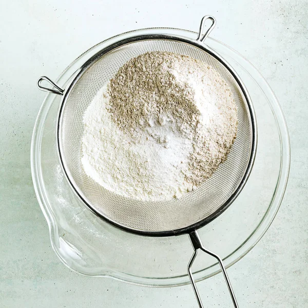 Przesiewanie Mąki Przez Sito Dużej Szklanej Miski — Zdjęcie stockowe