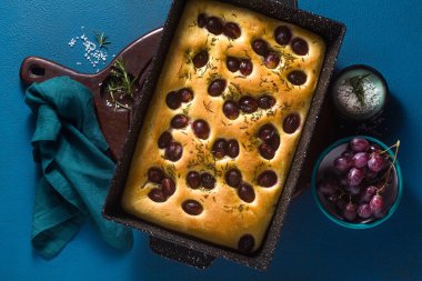 Mavi bir masada kırmızı üzümlü Focaccia. İtalyan mutfağı, mükemmel aperatif.