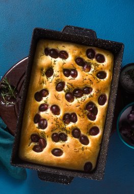 Mavi bir masada kırmızı üzümlü Focaccia. İtalyan mutfağı, mükemmel aperatif.