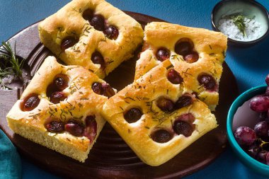 Mavi bir masada kırmızı üzümlü Focaccia. İtalyan mutfağı, mükemmel aperatif.