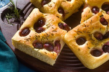 Mavi bir masada kırmızı üzümlü Focaccia. İtalyan mutfağı, mükemmel aperatif.