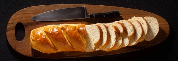 banner of sliced loaf of bread on a chopping board and a chef\'s knife on a black background