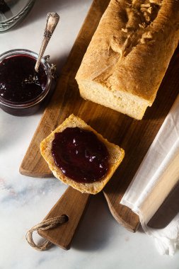 Taze ev yapımı ekmek ve reçel mutfak masasındaki kavanozda, koyu arkaplanda..