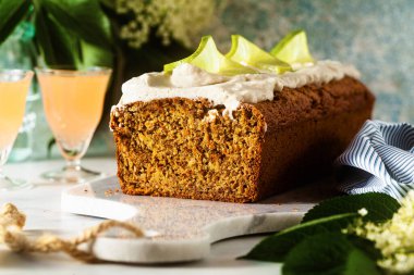 Masada çiçekli tatlı bir somun kek ve bardakta bir içki. Hindistan cevizi kremalı ve limonlu. Kahvaltıda tatlı ya da sabah kahvaltısı.