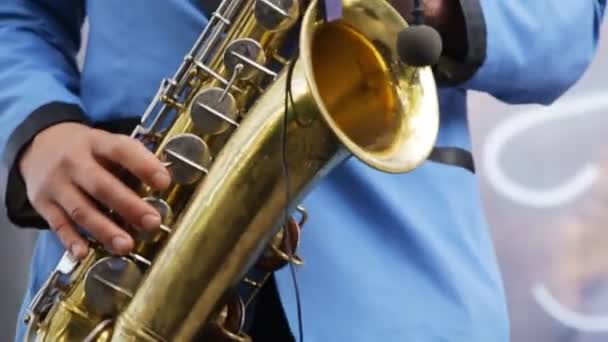 Muzikant spelen saxofoon close-up. Draadloze microfoon saxofoon. Man vingers op de toetsen van het muziekinstrument. Saxofonist in blauwe pak op gouden saxofoon spelen. Swing, jazz, bluesmuziek. — Stockvideo