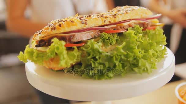 Sandwich auf einem Teller in Großaufnahme. Handschuss. Sandwich mit Fleisch, Salat, Käse, Tomaten. frische und leckere Hamburger. Fast Food. — Stockvideo