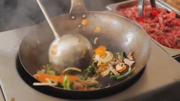 Επαγγελματική cook είναι ανάμειξη τηγάνισμα λαχανικών και κρέατος. Εσωτερικη ανακατώνει τα τηγανητά με μοσχάρι και λαχανικά. Διαδικασία του μαγειρέματος στο Φεστιβάλ φαγητό του δρόμου. — Αρχείο Βίντεο
