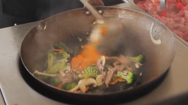 Επαγγελματική cook τηγάνισμα λαχανικών και κρέατος στο Φεστιβάλ των τροφίμων δρόμου. Εσωτερικη ανακατώνει τα τηγανητά με μοσχάρι και λαχανικά. Διαδικασία του μαγειρέματος. — Αρχείο Βίντεο