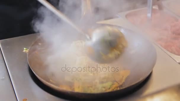 O cozinheiro profissional está fritando macarrão com legumes e carne no festival de comida de rua. Mexer fritar com carne e legumes de perto. Processo de cozimento. Tradicional comida asiática . — Vídeo de Stock