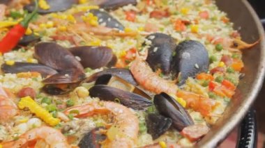 İspanyol paella sarı pirinç, karides ve gıda markette pişirme midye. Fotoğraf makinesi kaydırma. Sokak gıda Festivali. Geleneksel İspanyol yemeği. Pirinç kaynar su ürünleri ile yakın çekim.