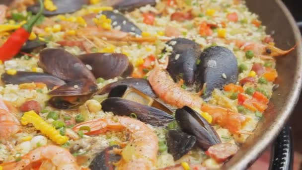 Spansk paella med gult ris, räkor och musslor matlagning på livsmedelsmarknaden. Panorera kameran. Gatan matfestival. Traditionell spansk mat. Ris med skaldjur kokande närbild. — Stockvideo