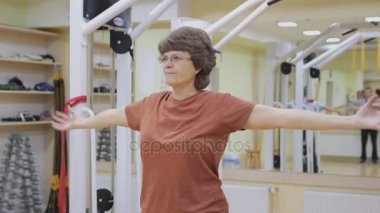 Yaşlı kadın uzanan, fitness odasında fizik tedavi egzersizleri yapıyor. Sağlıklı jimnastik. Aktif yaşlılar.