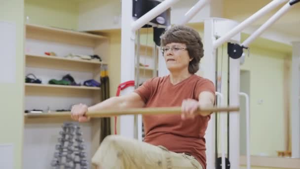 Eine ältere Frau streckt sich, macht im Fitnessraum Physiotherapieübungen mit Stock. Gesundes Turnen. Aktive Senioren. — Stockvideo