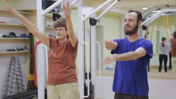 Młody mężczyzna i kobieta starszych rozciągania, ćwiczeń na siłowni. Gimnastyka na zdrowe. Osób aktywnych. — Wideo stockowe