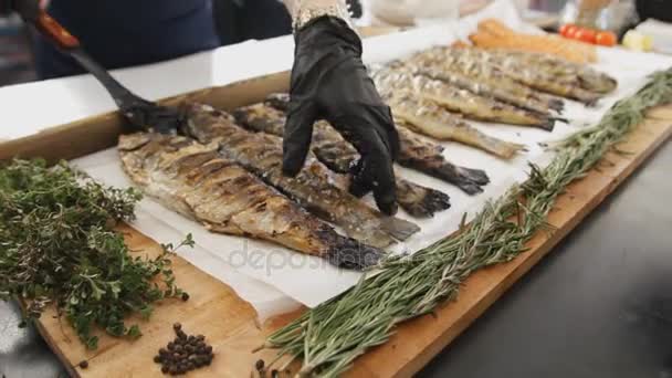 Жареная рыба с розмарином. Много приготовленной рыбы с зеленью на столе на фестивале еды. Вкусный лосось, приготовленный на барбекю . — стоковое видео