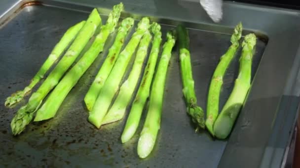 Gli asparagi verdi vengono fritti in una padella. Un cuoco sta mescolando gli asparagi . — Video Stock