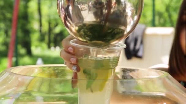 Mano femenina vertiendo limonada fresca en un vaso . — Vídeos de Stock